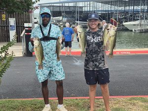 man in light blue shirt and shorts and cap holds 2 fish, man in grey shirt and shorts holds 2 fish