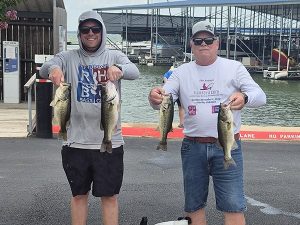 one man in RHBC hoodie holding 2 fish, man with grey shirt in ball cap holding 2 fish